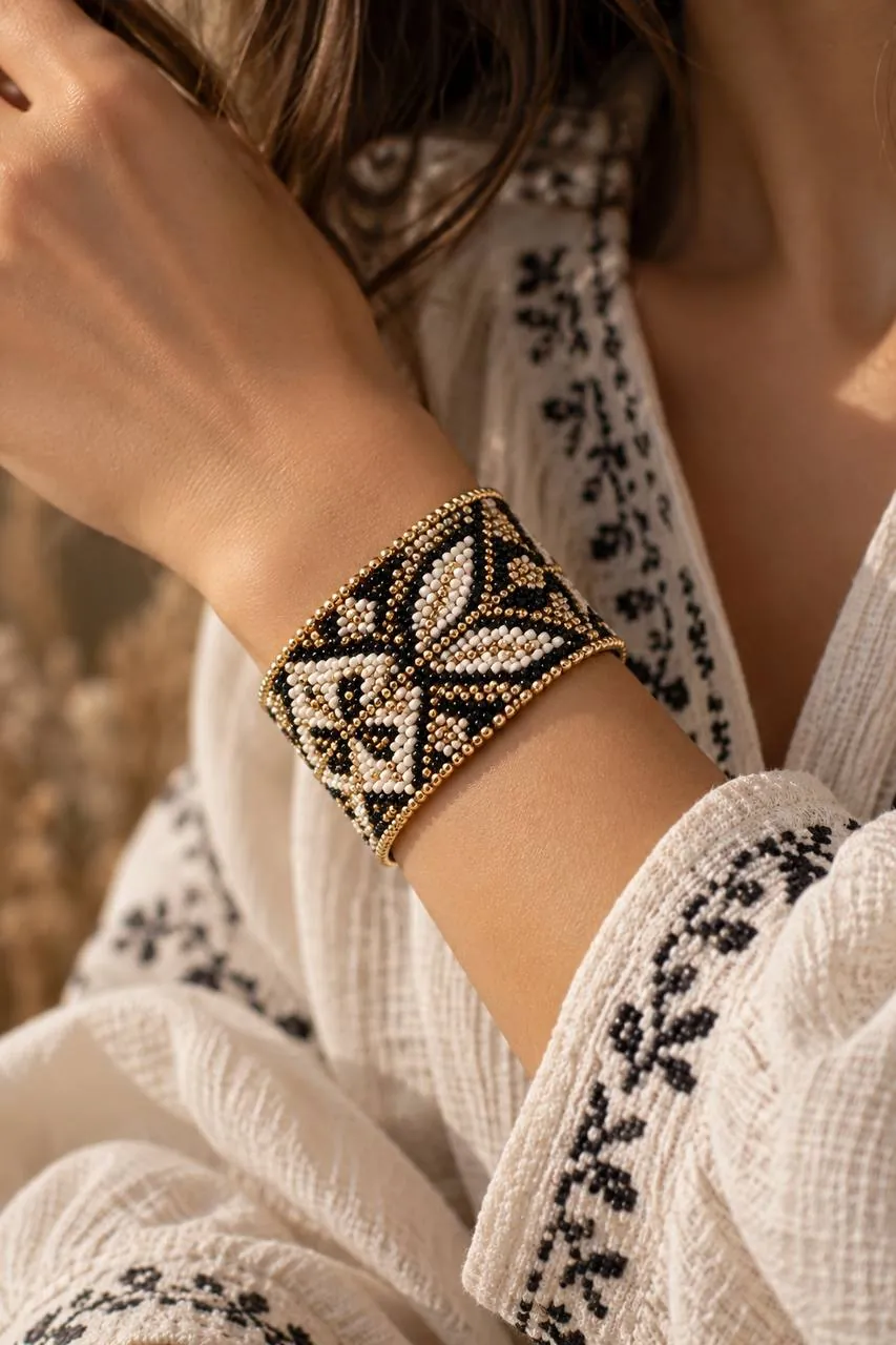 Black, cream and gold loom-woven cuff bracelet worn with an embroidered blouse