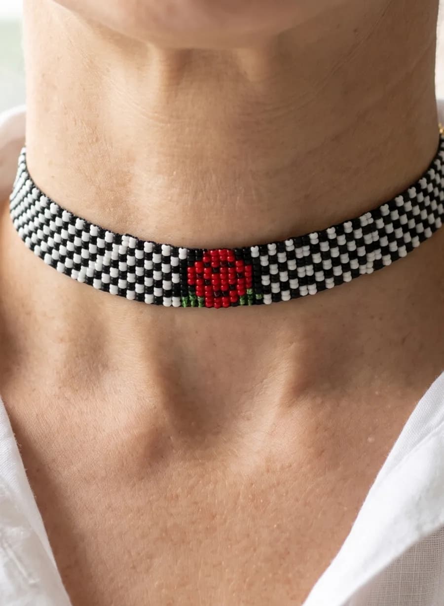 Square stitch choker with a black and white check and a red rose, worn